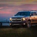 Black 2017 Chevrolet Tahoe SUV parked in grass in front of a city skyline