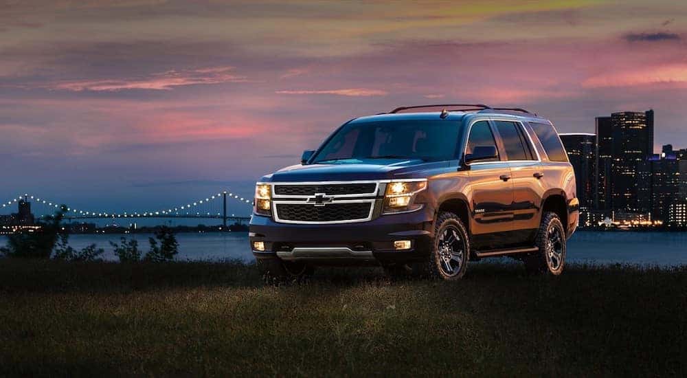 Black 2017 Chevrolet Tahoe SUV parked in grass in front of a city skyline