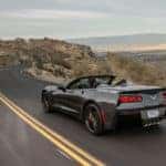 2018 Chevrolet Corvette Stingray convertible driving down a paved road past tall hills and mountains