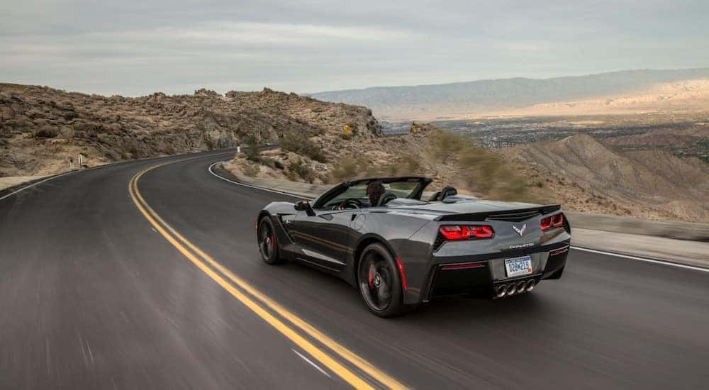 2018 Chevrolet Corvette Stingray convertible driving down a paved road past tall hills and mountains