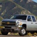 Silver 2013 Chevrolet Silverado 2500HD driving up a paved road in front of mountains