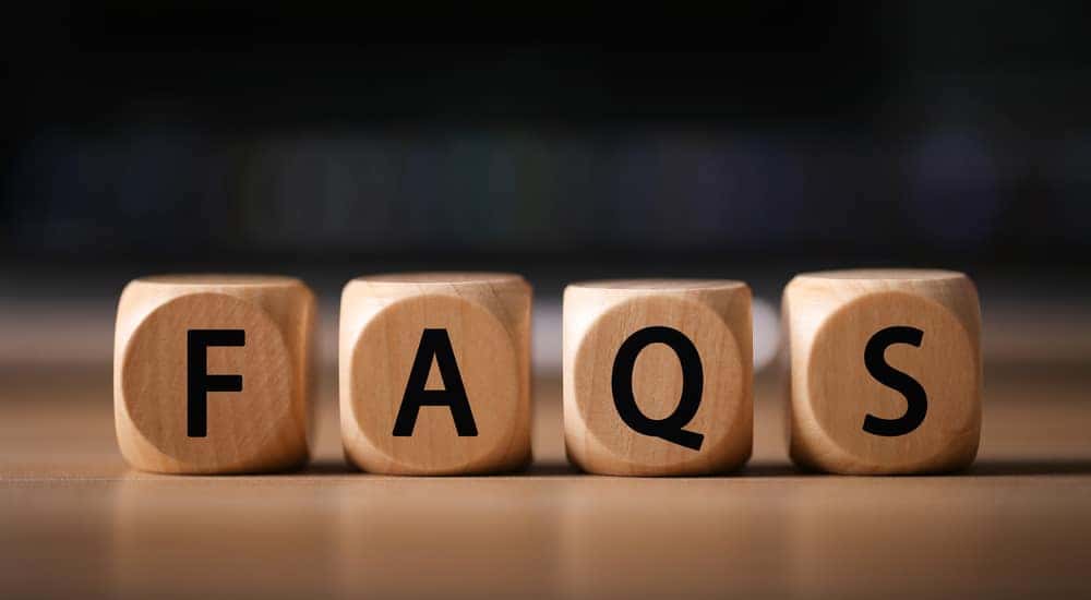 Four brown blocks with black letters on them spelling out "FAQS"