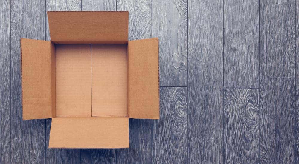 Open brown cardboard box sitting on a grey wooden floor