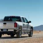 Back of a silver 2018 Chevrolet Silverado driving down a road toward mountains