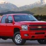 Red 2014 Chevrolet Silverado 2500HD parked on the street in front of water and mountains