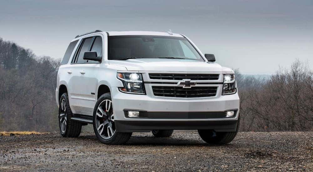White 2018 Chevrolet Tahoe parked near a cliff with trees in the background
