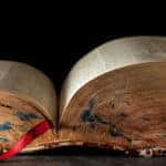 Large old book open with a red string bookmark sticking out