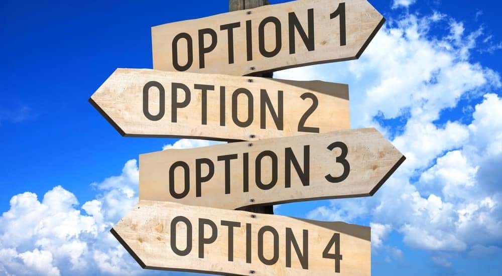 Four brown signs attached on top of one another, pointing in different directions with numbered options on them