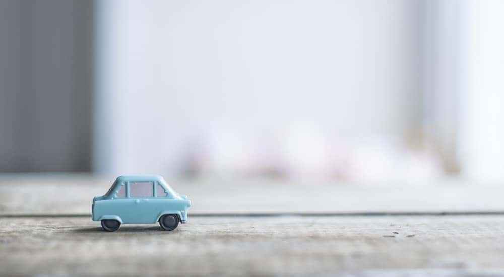 Small, light blue toy car sitting on a light grey table