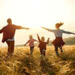 Family of four, all in red, running through a field of tall grass with their arms out