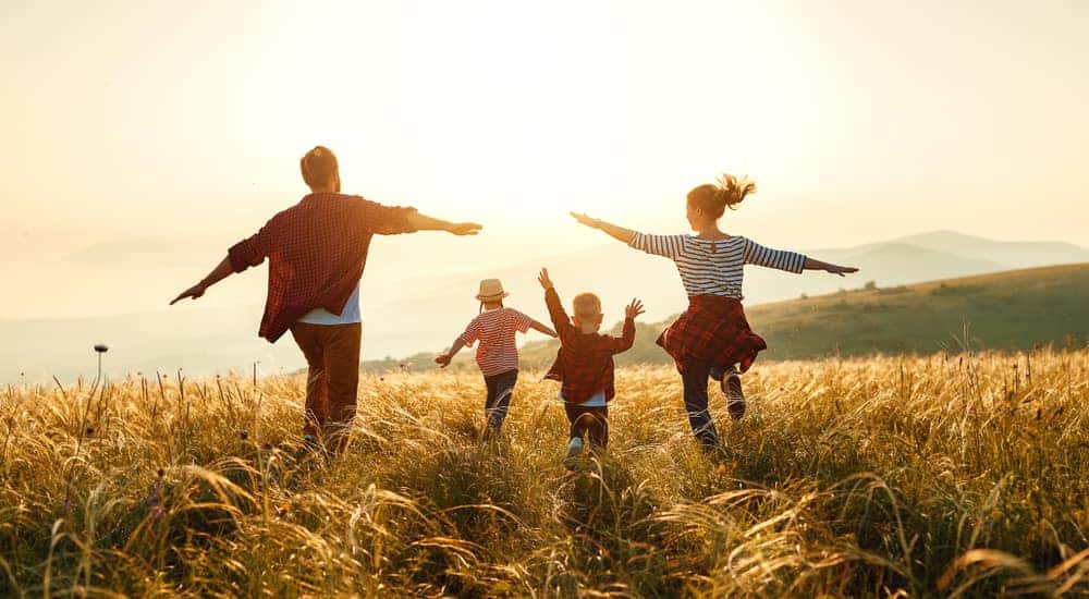 Family of four, all in red, running through a field of tall grass with their arms out