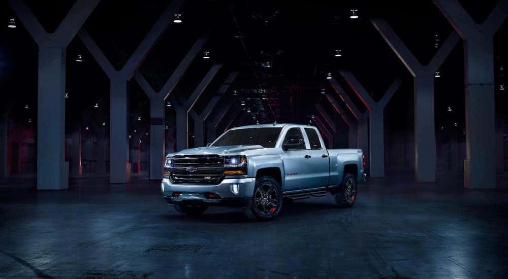 Silver 2018 Chevrolet Silverado Redline edition pickup truck in an all black room