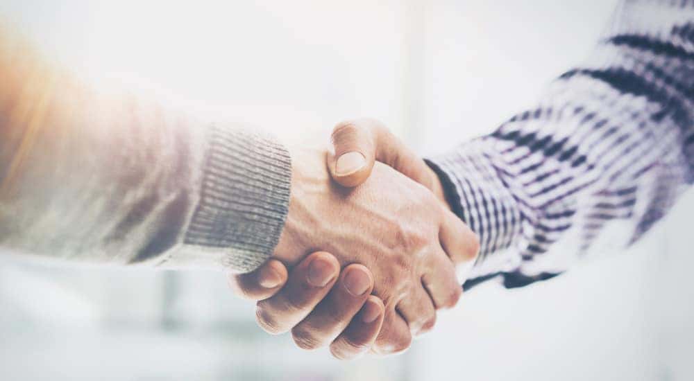 Handshake between an arm in a plaid shirt and an arm in a grey sweater