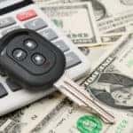 Pile of cash with a calculator and car key on top