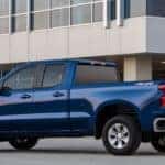 Blue 2019 Chevrolet Silverado parked on cement in front of a silver and glass building