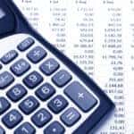 Calculator with the word "BUDGET" on the screen sitting on top of a printed spreadsheet with numbers on it