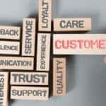 Brown blocks placed on a grey table with various words in black lettering on them, and "CUSTOMER" written in red on the biggest one