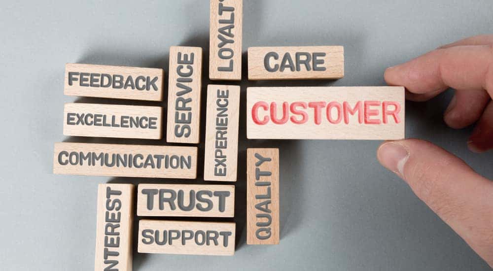 Brown blocks placed on a grey table with various words in black lettering on them, and "CUSTOMER" written in red on the biggest one