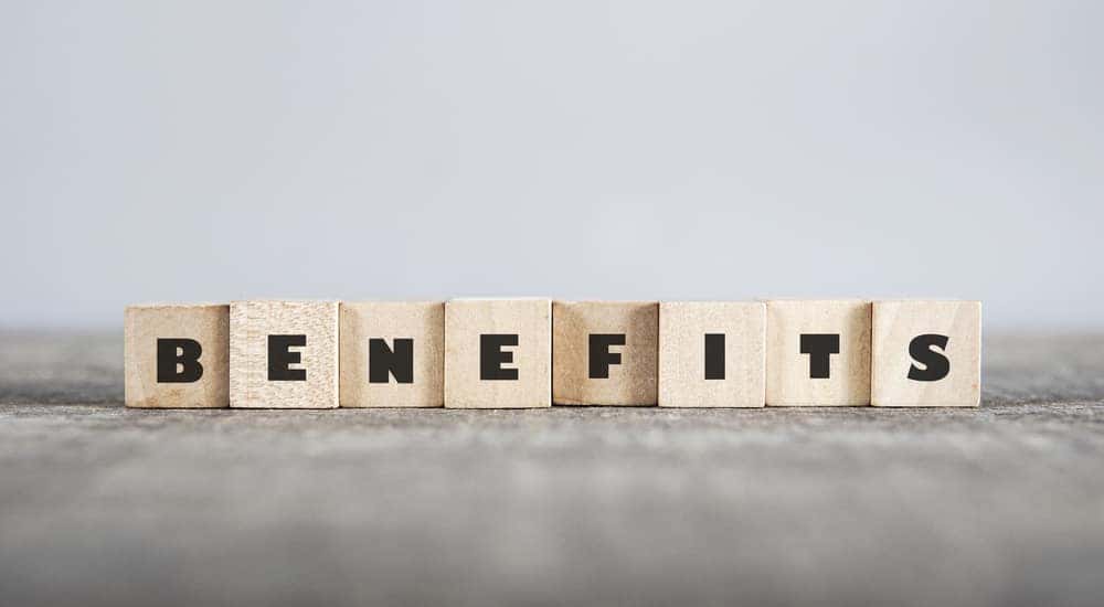 Light wood blocks that spell out "BENEFITS" sitting on a dark table