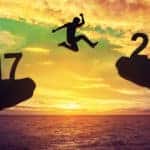 Silhouette of a man jumping from a cliff with the silhouette of "2017" on it to one with "2018" on it