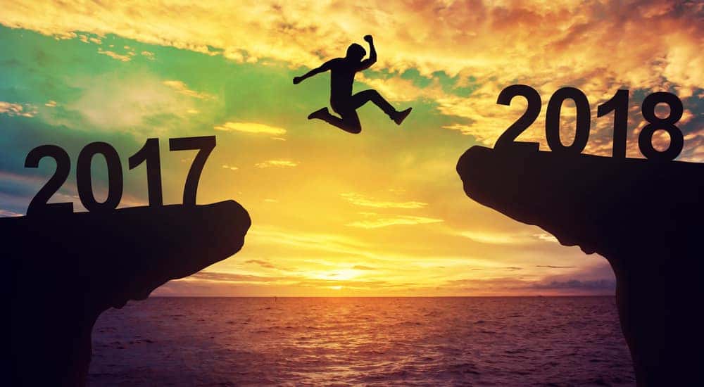 Silhouette of a man jumping from a cliff with the silhouette of "2017" on it to one with "2018" on it