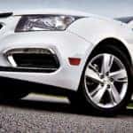 Closeup of a white 2015 Chevy Cruze front end parked on a paved surface