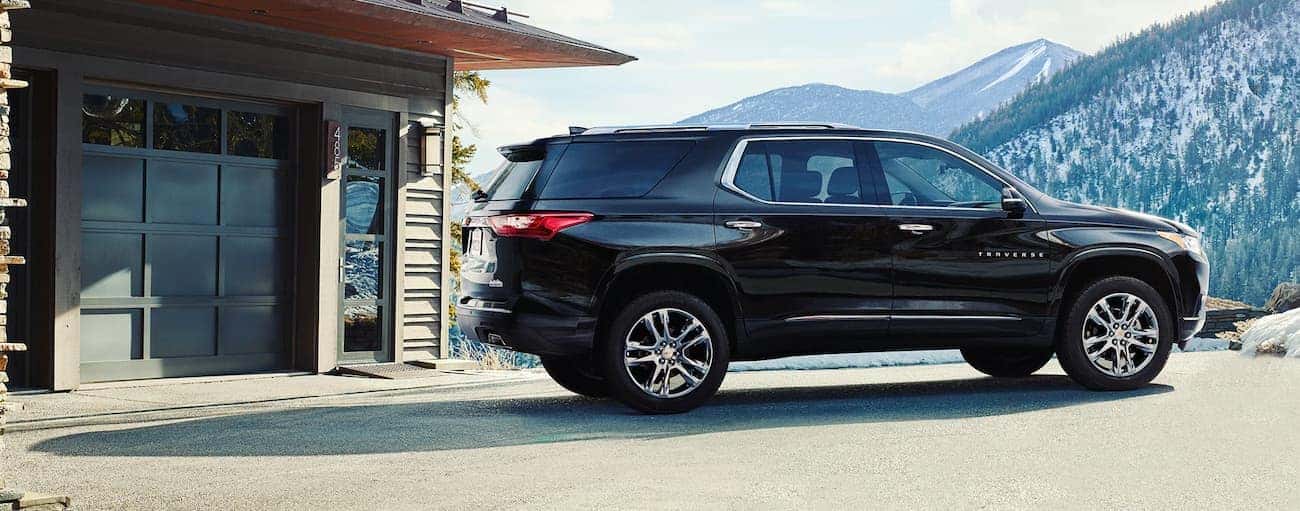 A black 2020 Chevy Traverse is parked outside a home near Albany, NY, with mountain views.