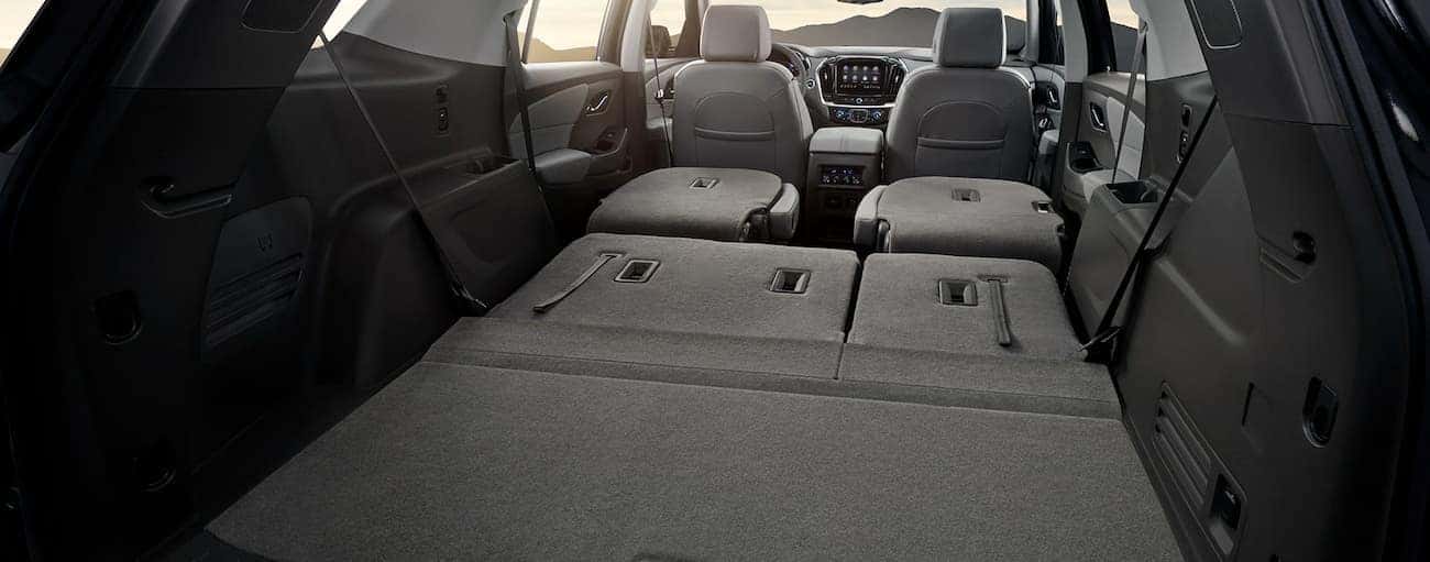 The seats are folded down to show the cargo room in the grey interior of a 2020 Chevy Traverse.