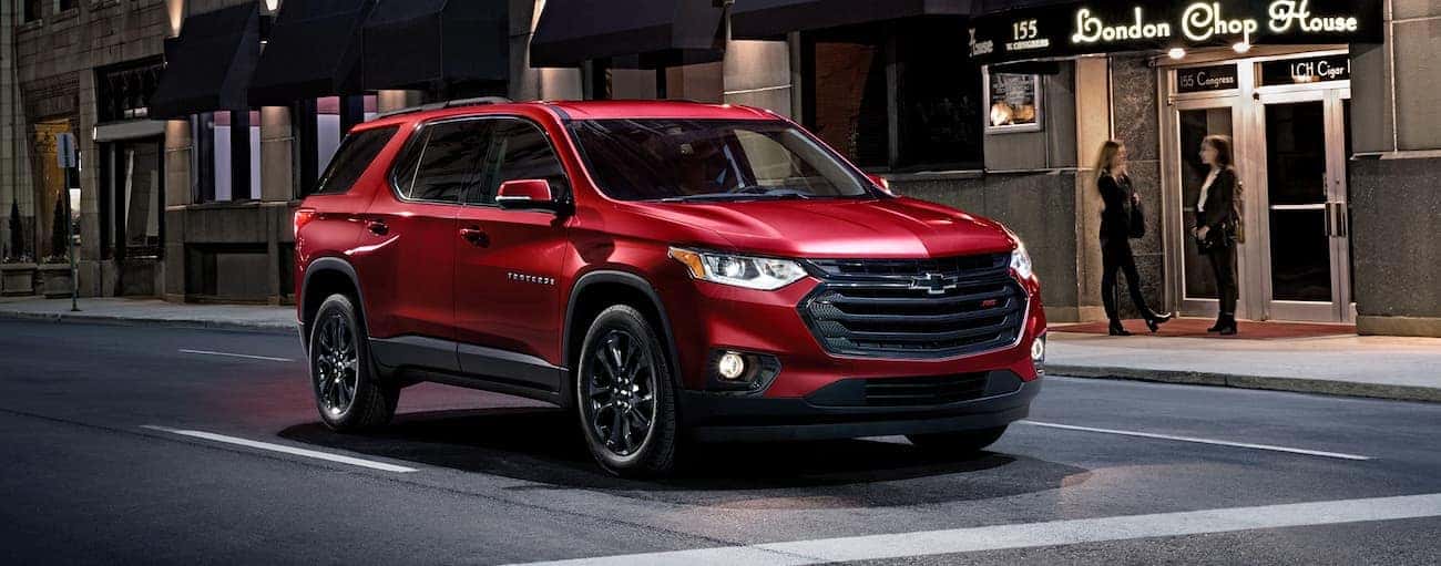 A red 2020 Chevy Traverse RS is stopped at a city intersection at night near Albany, NY.
