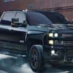 A black 2019 Chevy Silverado 2500HD, one of the best selling Chevy trucks in Albany, NY, is driving through rain.