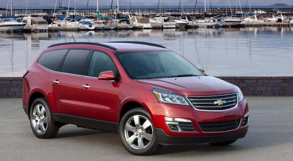 Red 2016 Chevrolet Traverse parked in front of a body of water with boats in the background