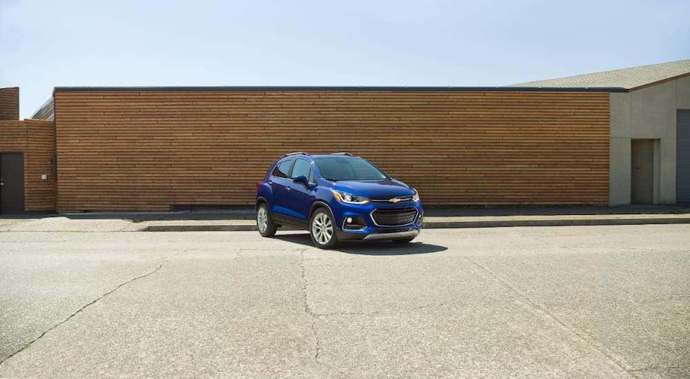 Blue 2017 Chevrolet Trax SUV parked on cement in front of a brown wall