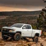 White 2020 Chevrolet Colorado parked on a large rock mountain with other mountains in the distance