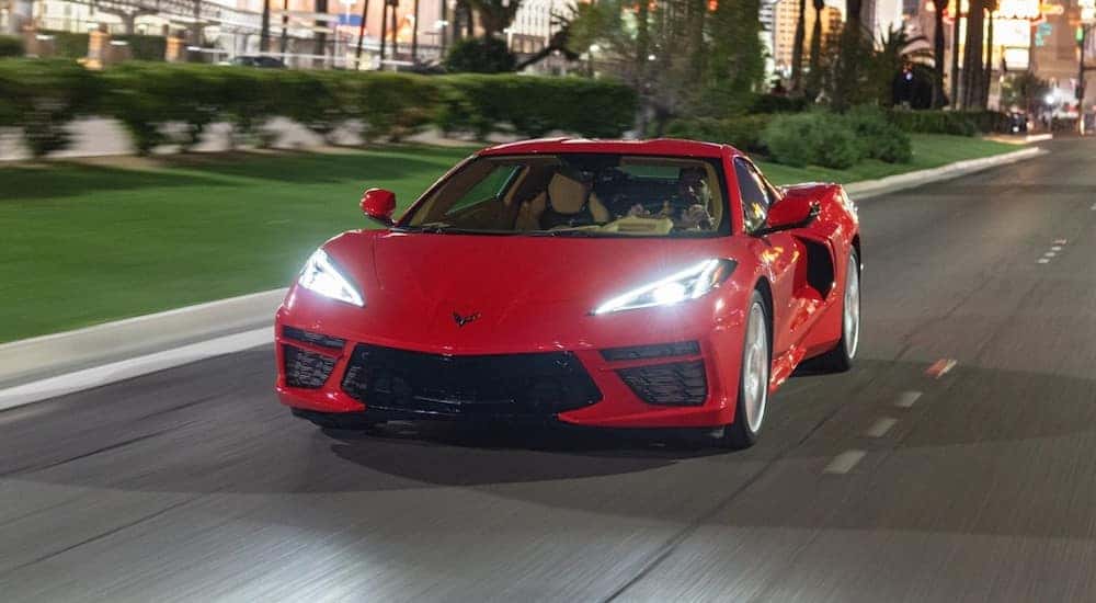 Red 2020 Chevrolet Corvette Stingray driving down a paved road next to green grass