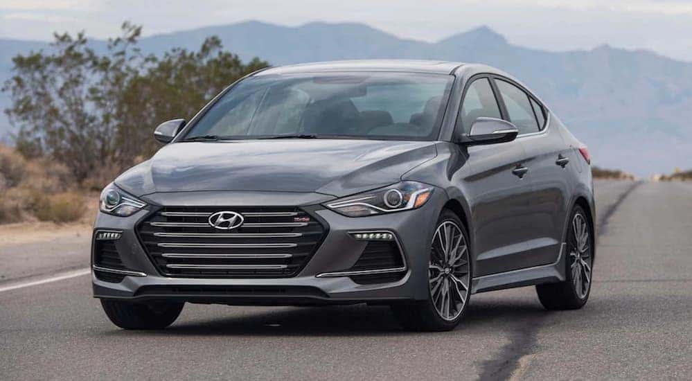 A grey 2017 Hyundai Elantra is parked on a road with mountains in the distance.