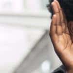 Man holding his hand up to his ear to hear better