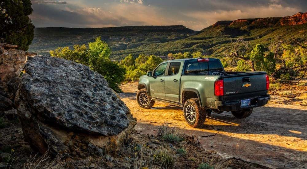 Green 2020 Chevrolet Colorado driving down a dirt road with rocks and mountains on both sides
