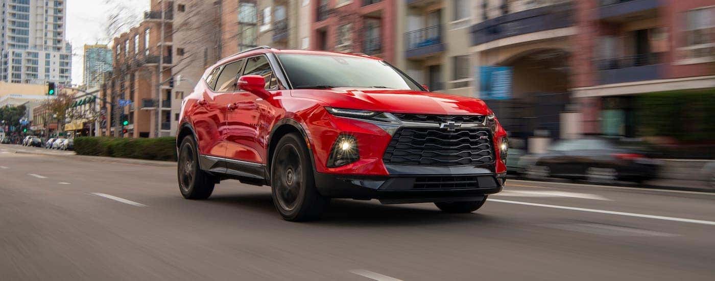 A red 2020 Chevy Blazer RS is driving on a downtown street near Clifton Park, NY.