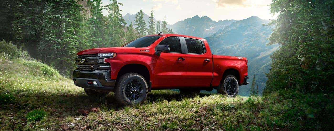 A red 2020 Chevy Silverado 1500 is off-roading near mountains.