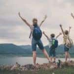 A family has their arms up in excitement while looking over a large lake after hiking near Clifton Park, NY.