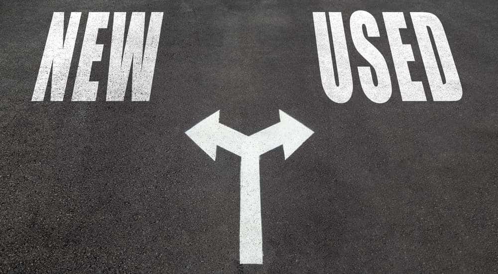 Pavement with the words "NEW" and "USED" written on it in white and a white arrow with two points going in opposite directions