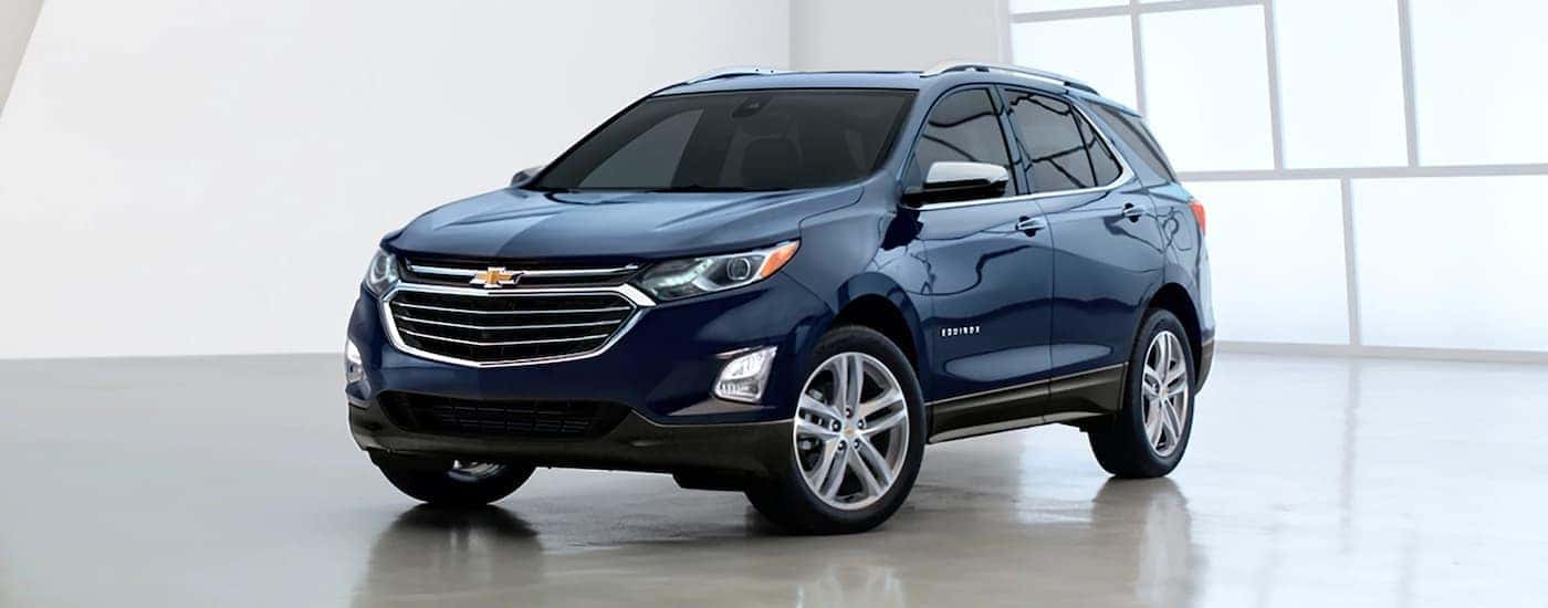 A blue 2020 Chevy Equinox is parked in a white showroom.