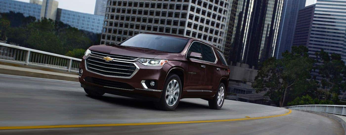 A burgundy 2020 Chevy Traverse is driving out of the city.