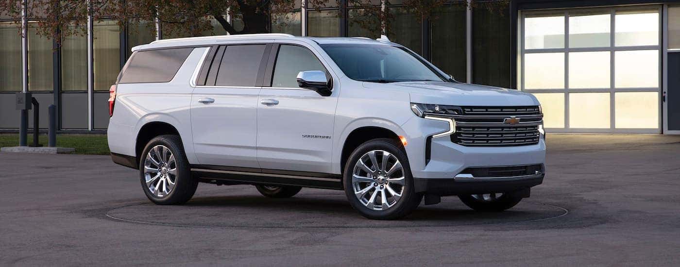 A white 2021 Chevy Suburban, the largest of the Chevy SUVs, is in front of an office building near Albany, NY.