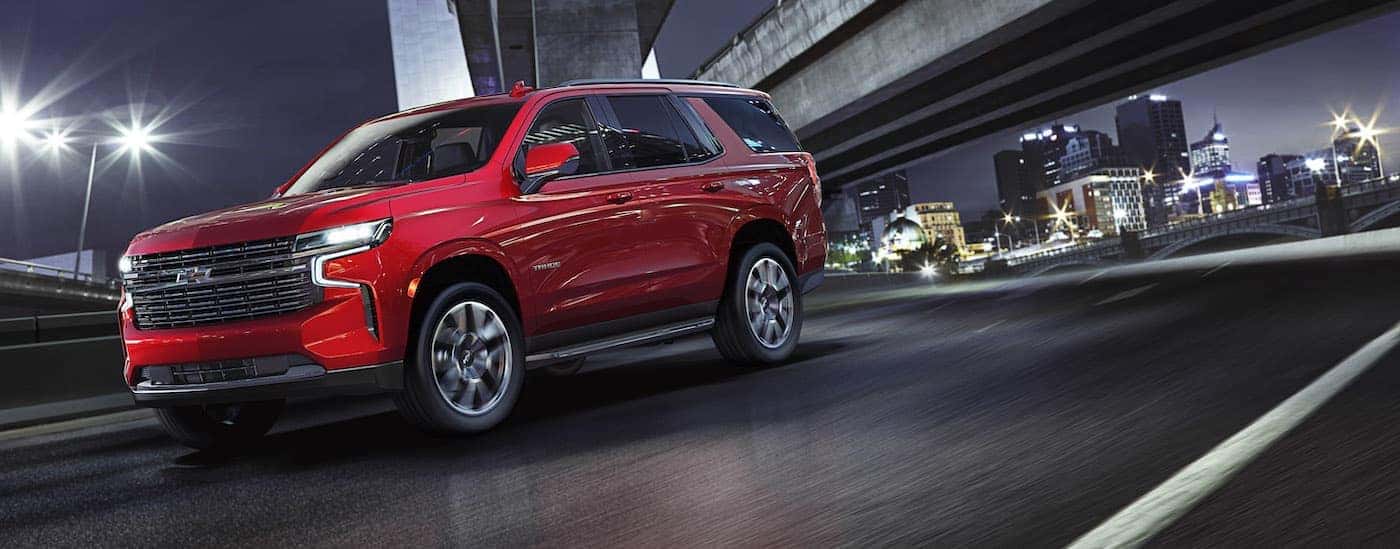 A red 2021 Chevy Tahoe RST is driving past a city at night.