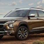 A brown 2021 Chevy Trailblazer is parked on dirt with desert hills in the distance.