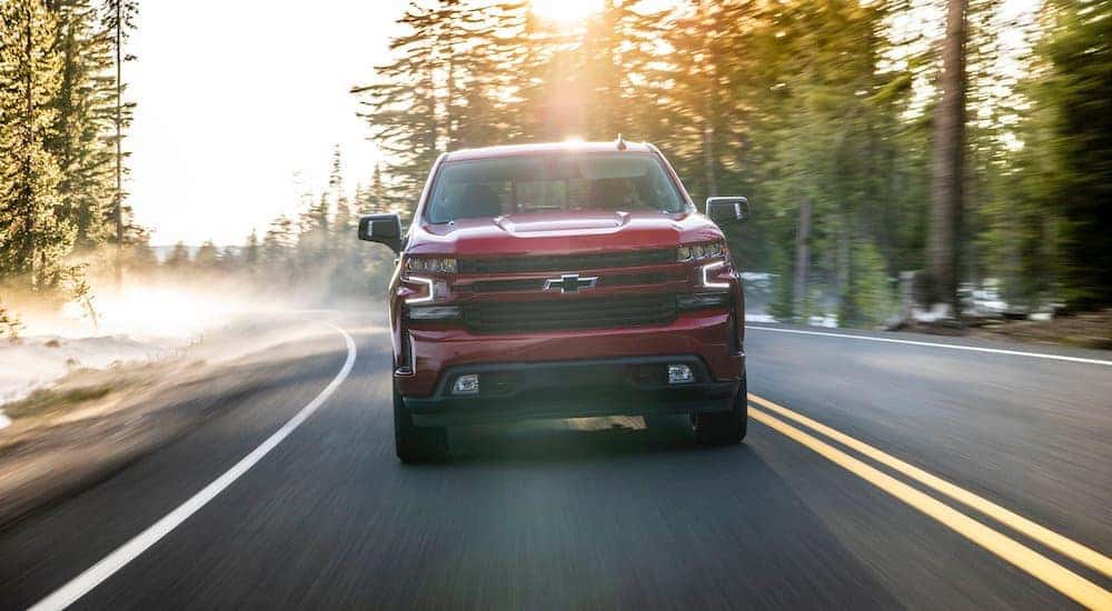 A red 2020 Chevy Silverado 1500, which is popular among trucks for sale in ALbany, NY, is driving on a misty road.