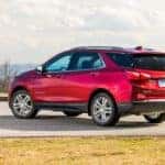 Red 2020 Chevrolet Equinox parked on pavement between patches of grass with mountains in the distance