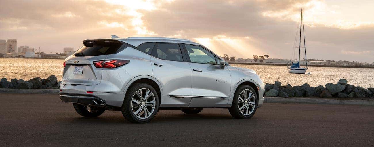 A silver 2020 Chevy Blazer is overlooking a boat in a marina against a vibrant yellow sky.