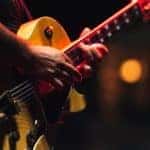 A closeup of someone playing a yellow electric guitar